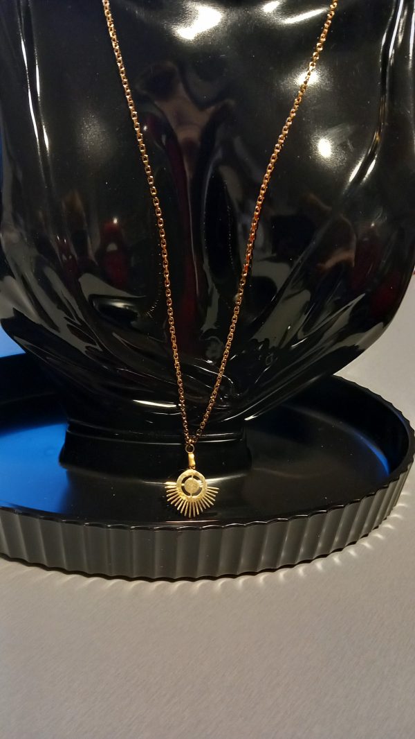 Collier en acier inoxydable fabriqué avec une chaîne fine dorée et un pendentif.
