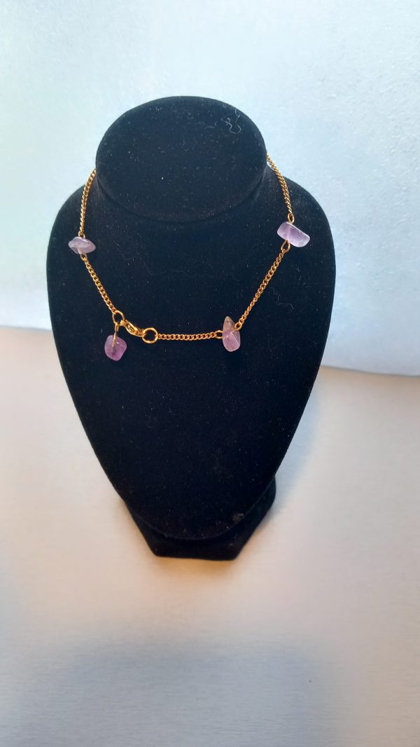 Bracelet fabriqué avec une chaîne fine dorée en acier inoxydable et des pierres semi-précieuses d'Améthyste.